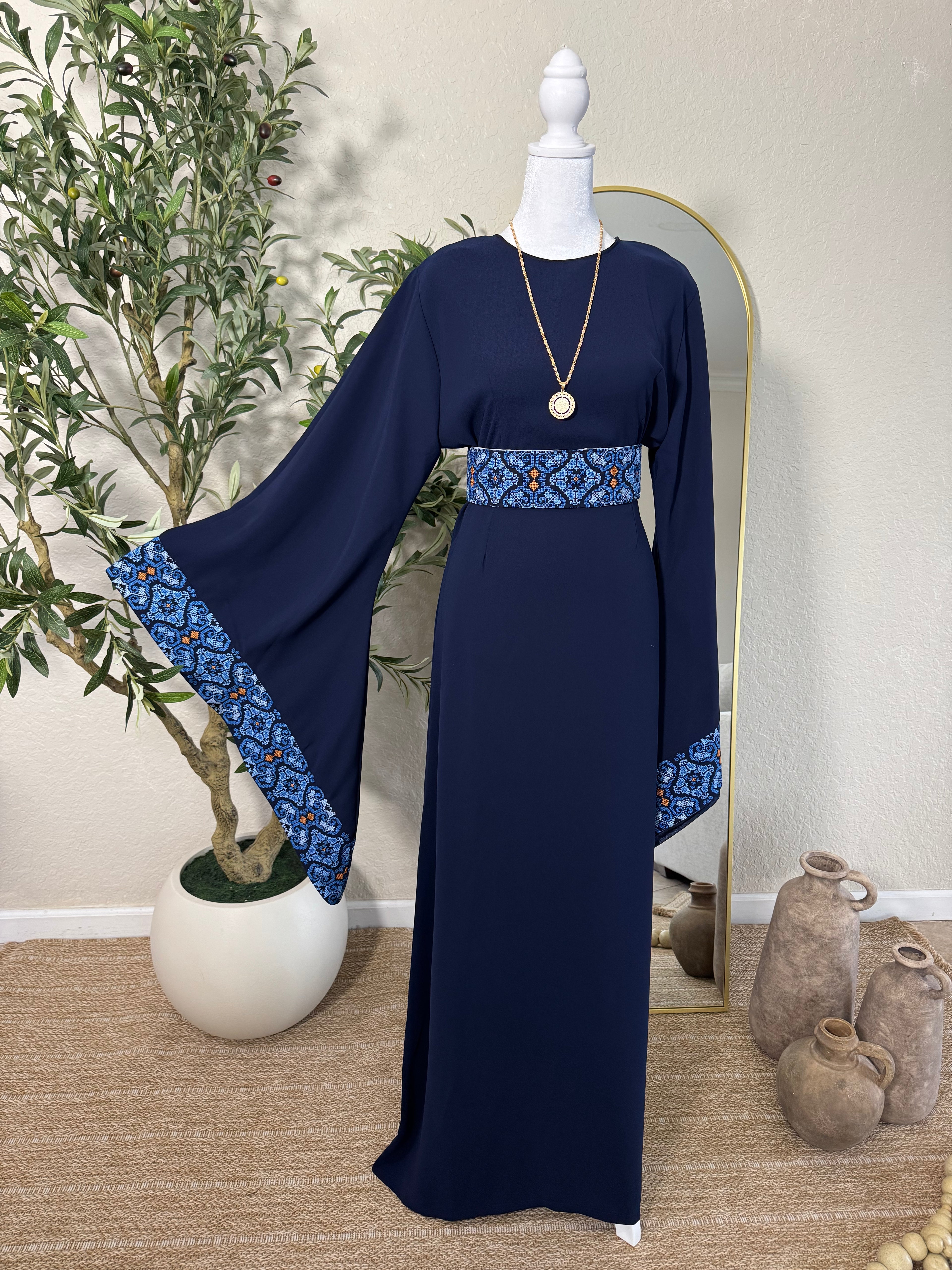 Luxury navy modest thoub by Amira Designs featuring intricate blue Palestinian-inspired embroidery, flowing wide sleeves, and elegant heritage detailing