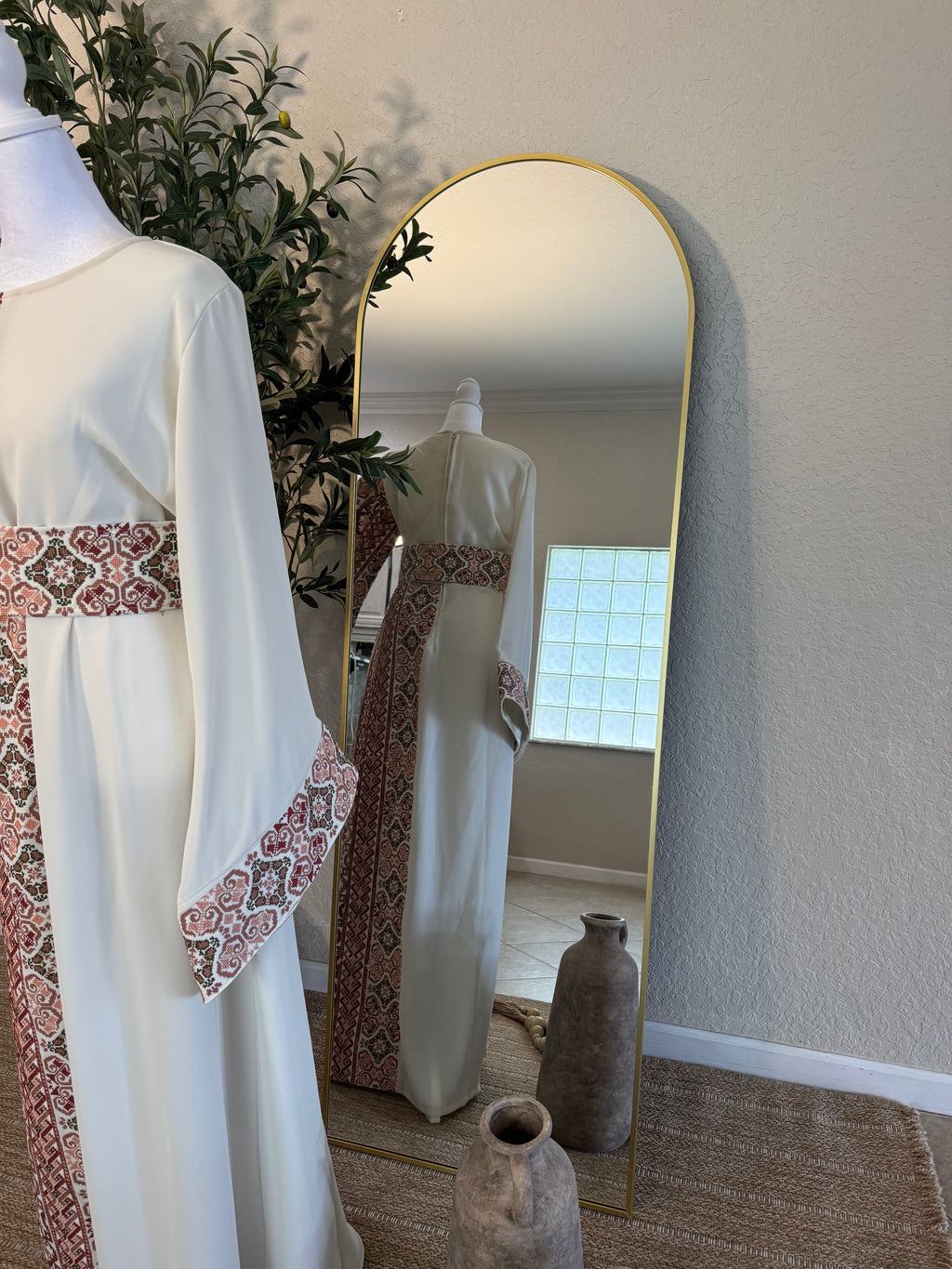 The Rosewater Thoub displayed on a mannequin features intricate traditional embroidery along the waist and sleeves, styled in an elegant, modest fashion setting.