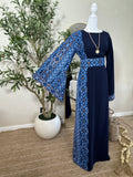 The Sapphire Thoub displayed on a mannequin features elegant blue and black embroidered patterns on the sleeve, waist, and side panels, showcasing luxury modest fashion with traditional Palestinian design elements.