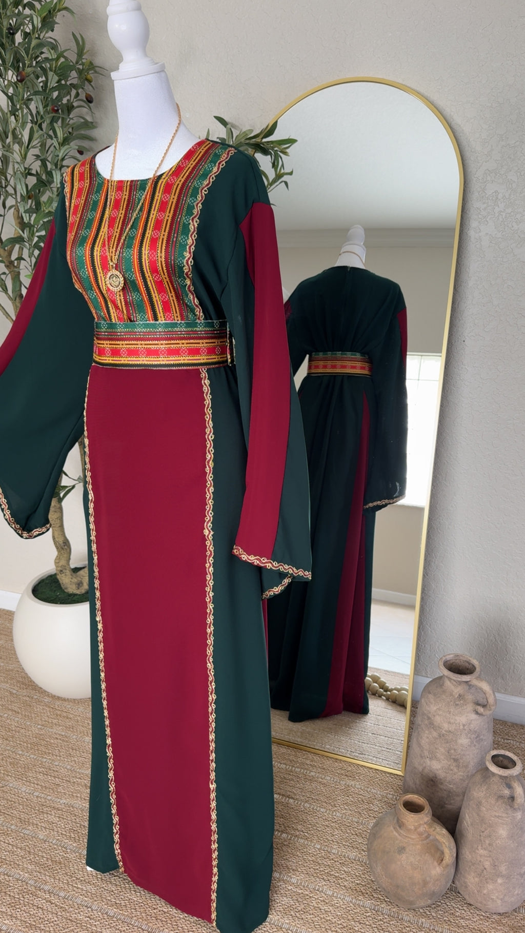 The Sultana Thoub showcases a traditional Palestinian embroidered abaya with rich green and deep red panels, elegant gold trim, and a matching patterned belt for a luxurious modest fashion statement.
