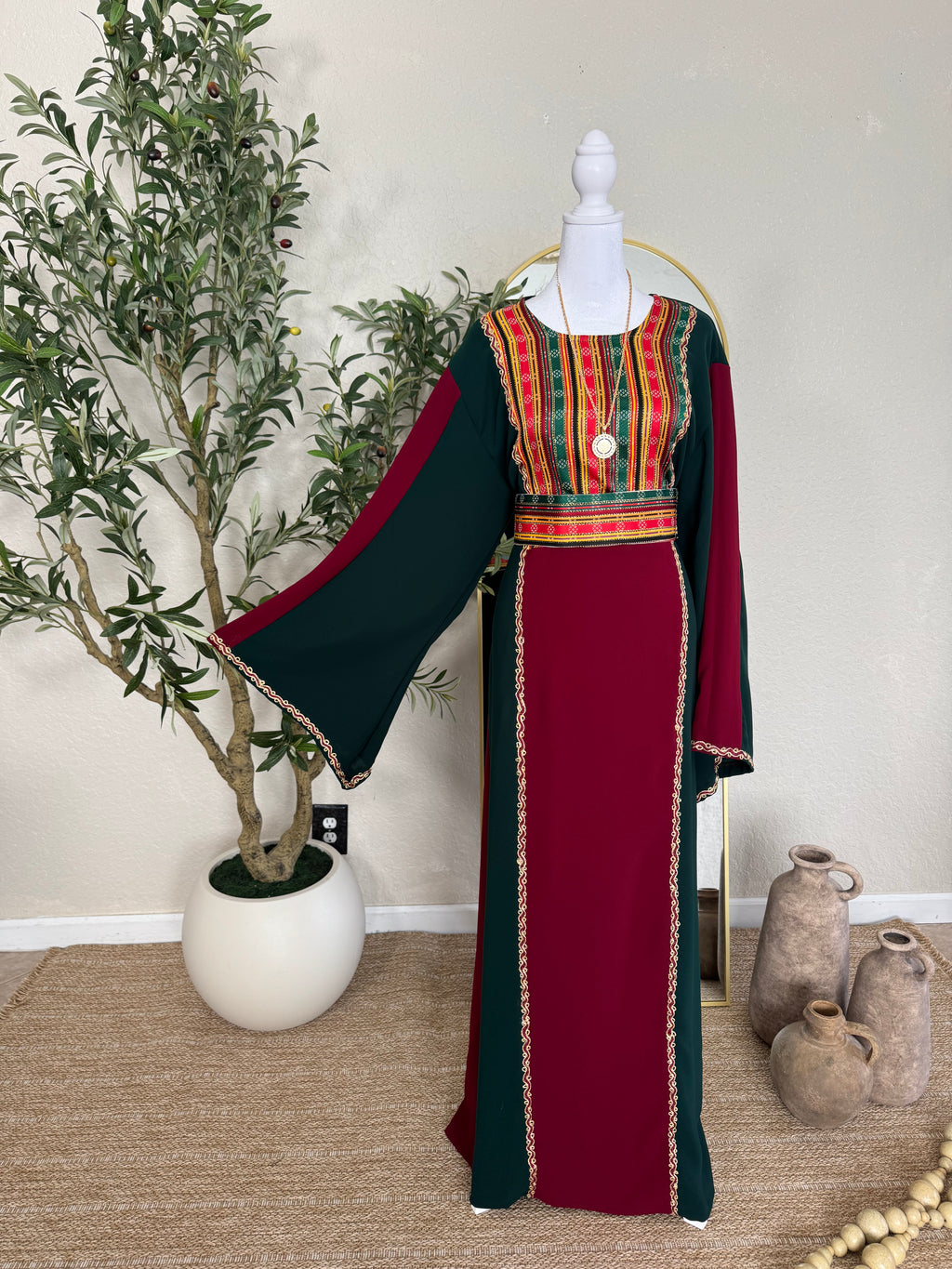 The Sultana Thoub featuring traditional Palestinian embroidery on a rich burgundy and dark green fabric with wide flowing sleeves, elegant and handcrafted modest fashion dress.