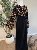 Elegant black modest dress with floral embroidered sleeves and flowing silhouette