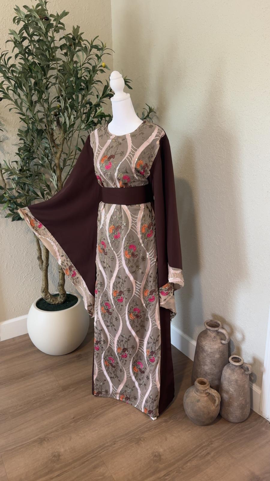 Front angled view of The Jericho Bloom Palestinian Abaya with chocolate brown wide sleeves and colorful floral embroidery