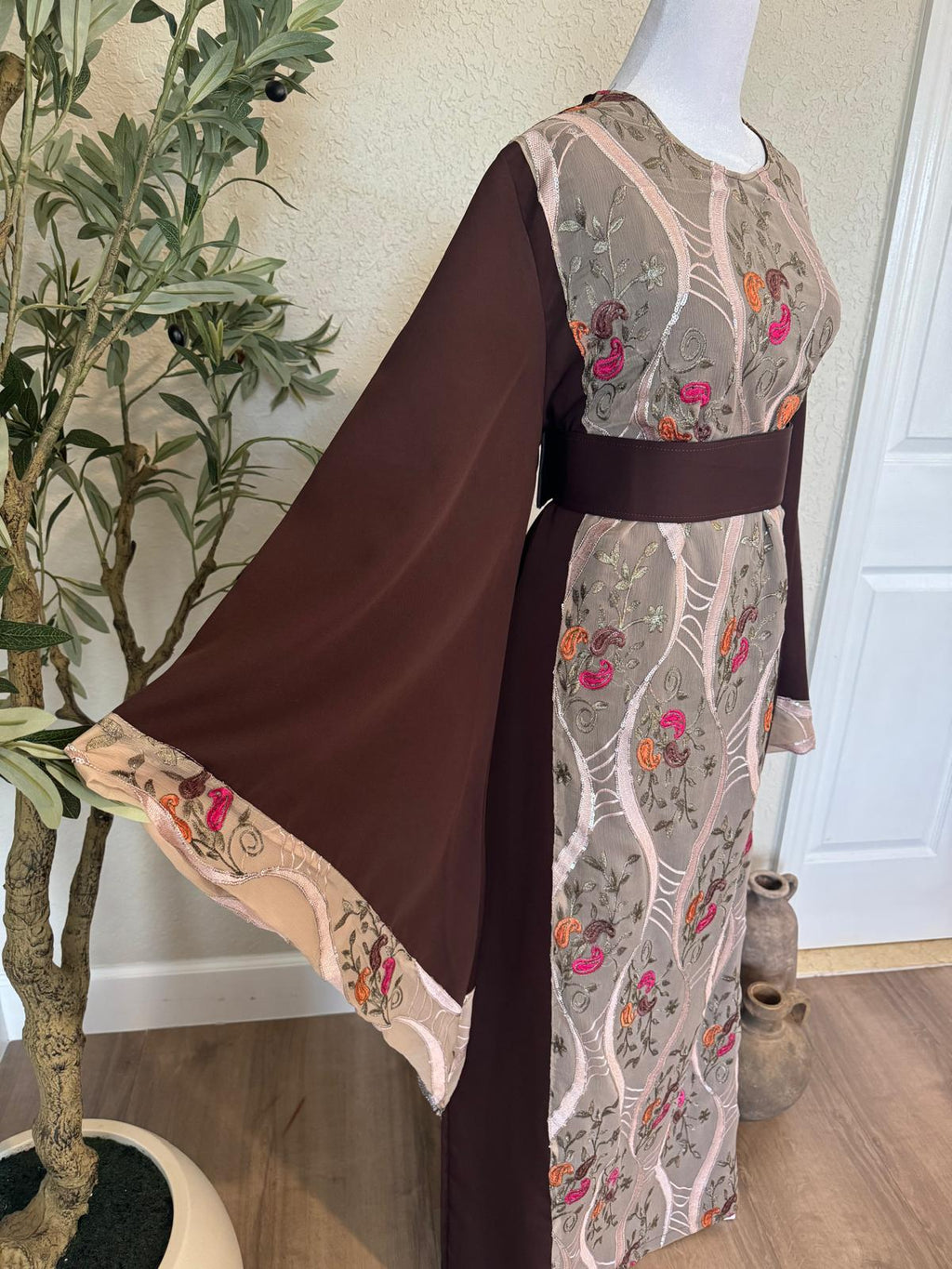 Close view of The Jericho Bloom Palestinian Abaya showing wide chocolate brown sleeve and pink orange floral embroidered border