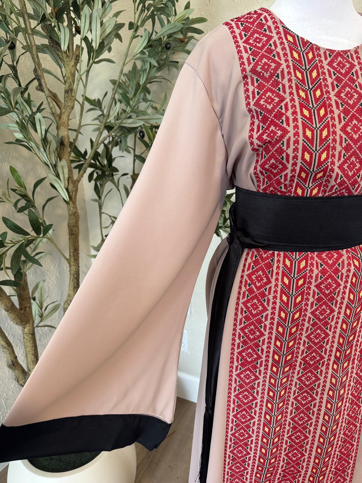 Close-up of The Ramallah Ruby Abaya showing red geometric front pattern, wide taupe sleeve and contrasting black belt