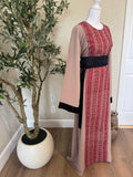 Front angled view of The Ramallah Ruby Palestinian Abaya with red geometric patterned panel, dusty taupe fabric and black belt