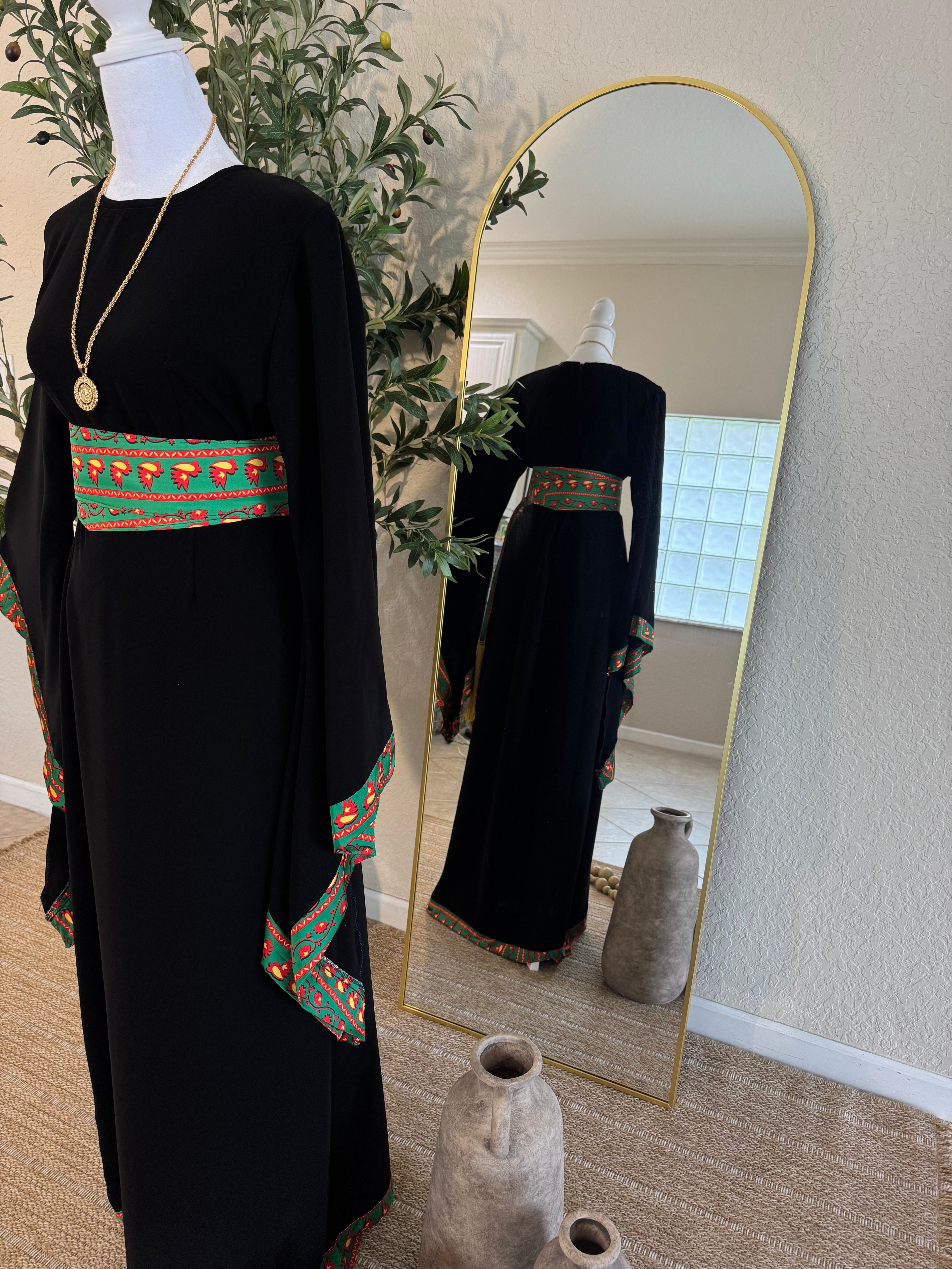 Elegant modest black abaya featuring colorful traditional woven detailing on sleeves and waist